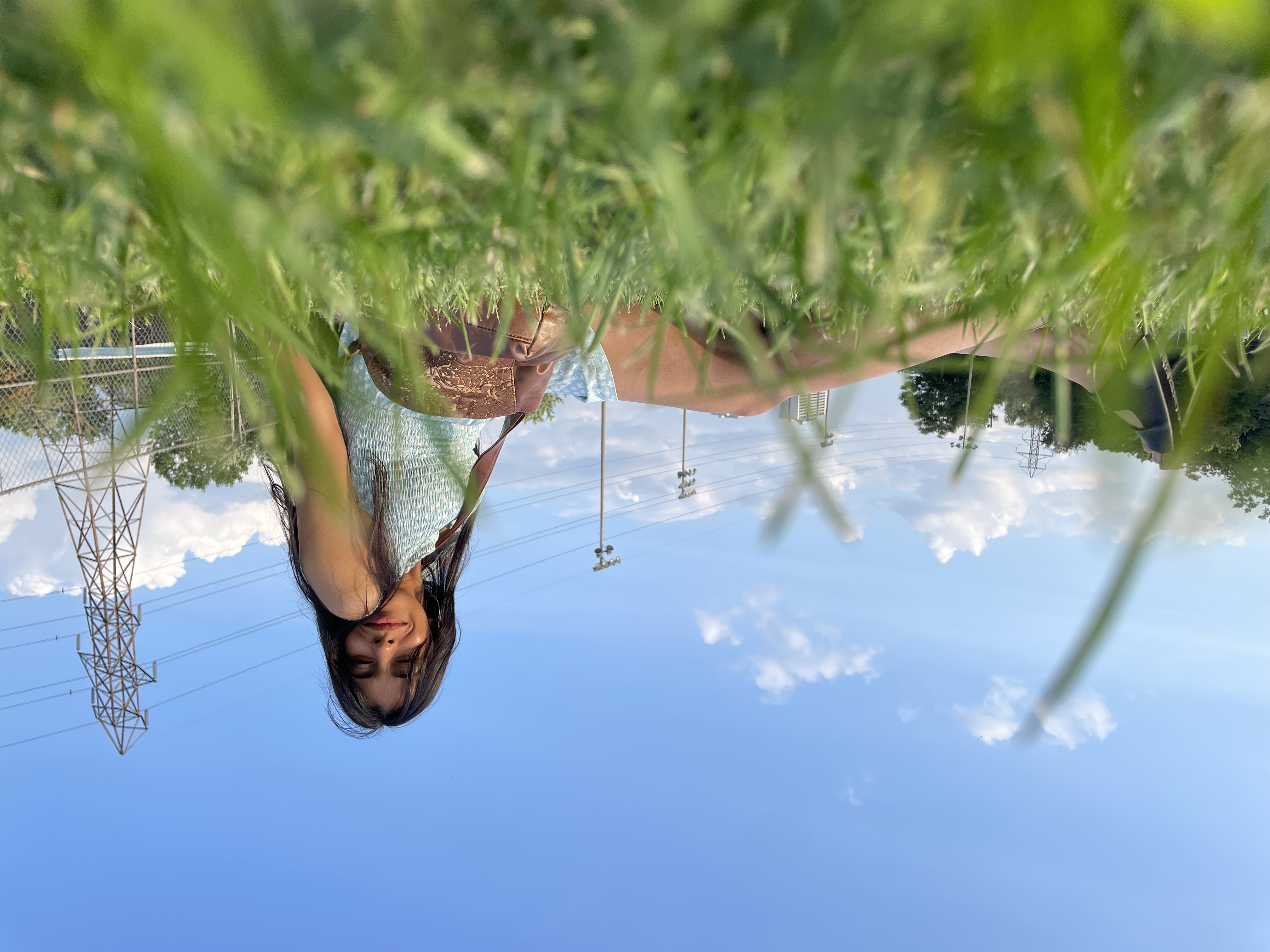 Astha relaxing in the grass beneath an open blue sky